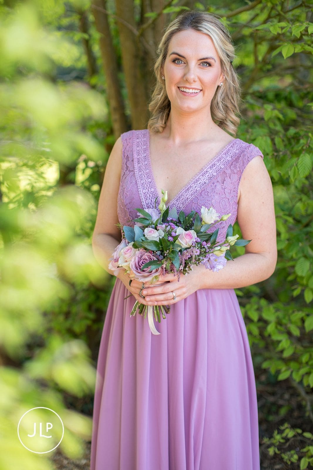 Portrait of a bridesmaid holding flowers by a Surrey wedding photographer at Langshott Manor.
