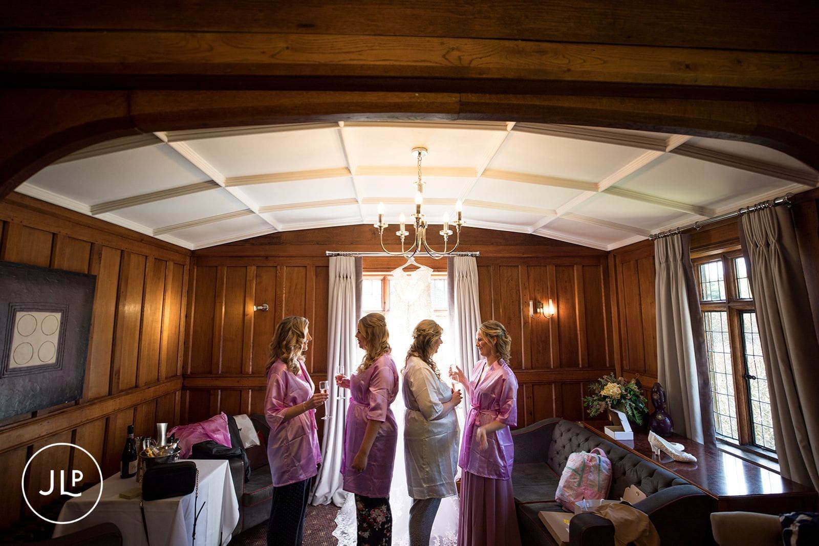 Bridesmaids in silk robes toast the bride inside a luxury Surrey wedding venue suite.