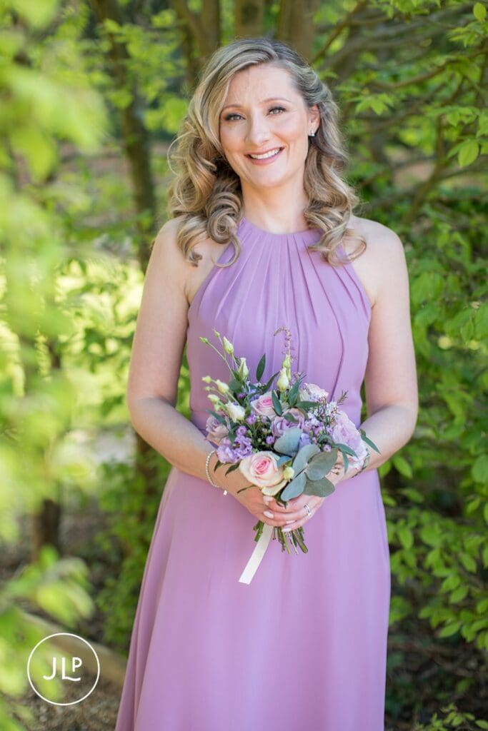Bridesmaid in a lilac dress holding a bouquet at a Langshott Manor wedding in Surrey.