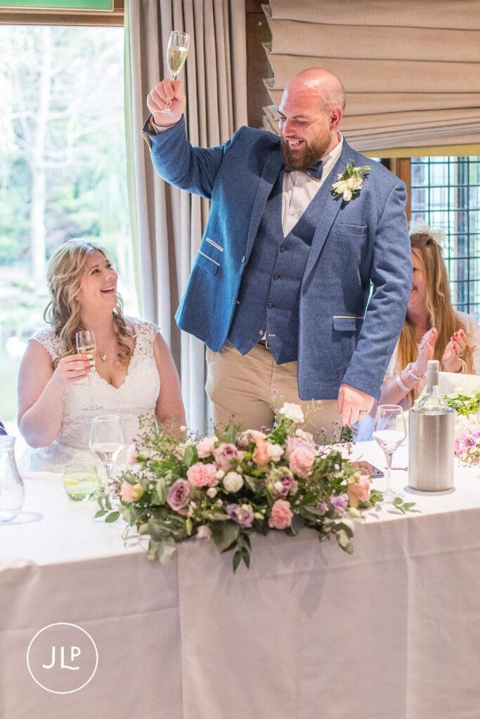 The groom standing to give a toast next to his bride at their Langshott Manor wedding in Surrey.