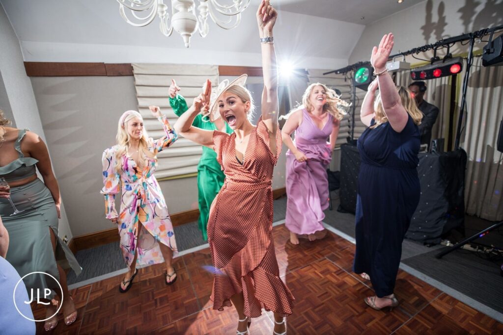Wedding guests dancing and celebrating under party lights at a lively evening reception in Surrey.