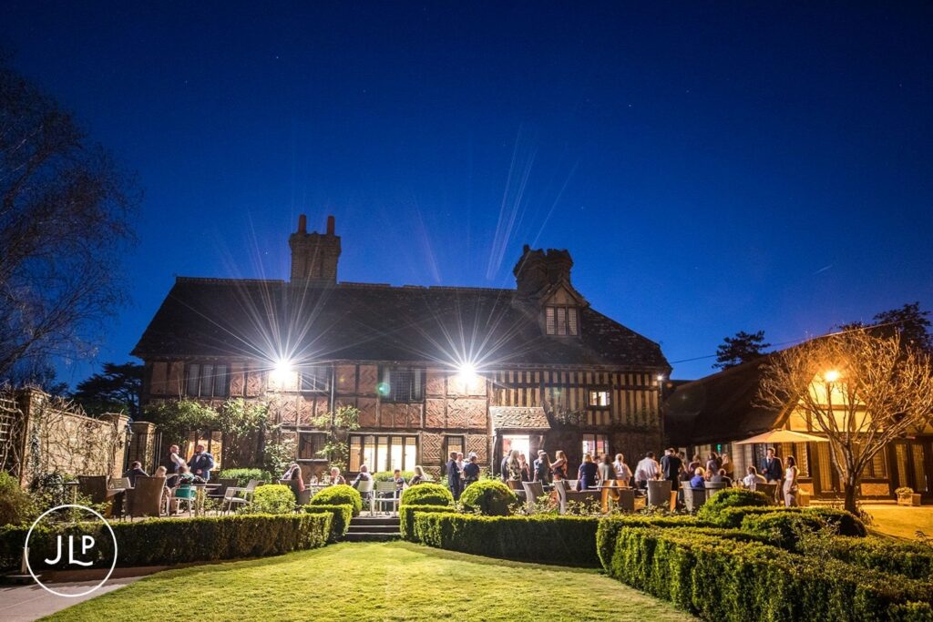 The exterior of the historic Langshott Manor illuminated at night during a beautiful evening wedding reception.