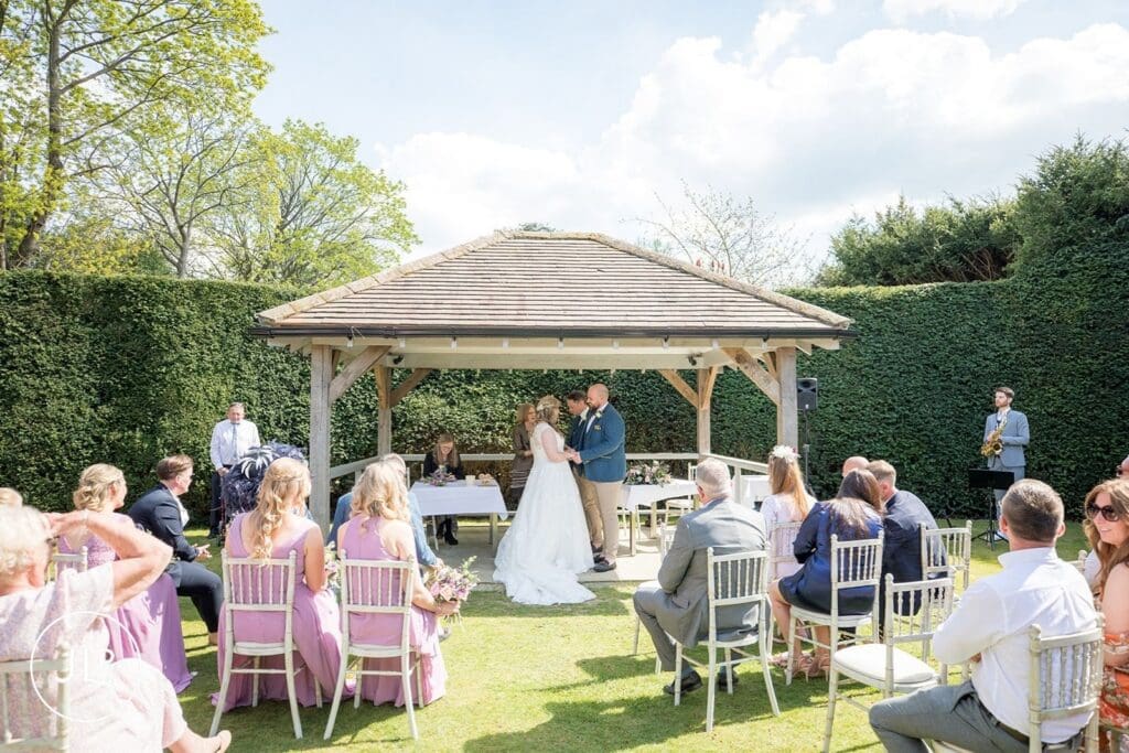 Romantic outdoor wedding ceremony at the Langshott Manor gazebo, a historic Surrey wedding venue.