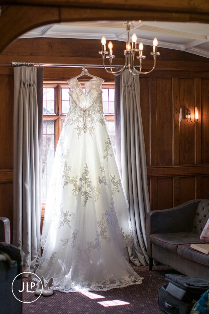 Elegant wedding dress hanging in a characterful room at Langshott Manor luxury Surrey wedding venue.