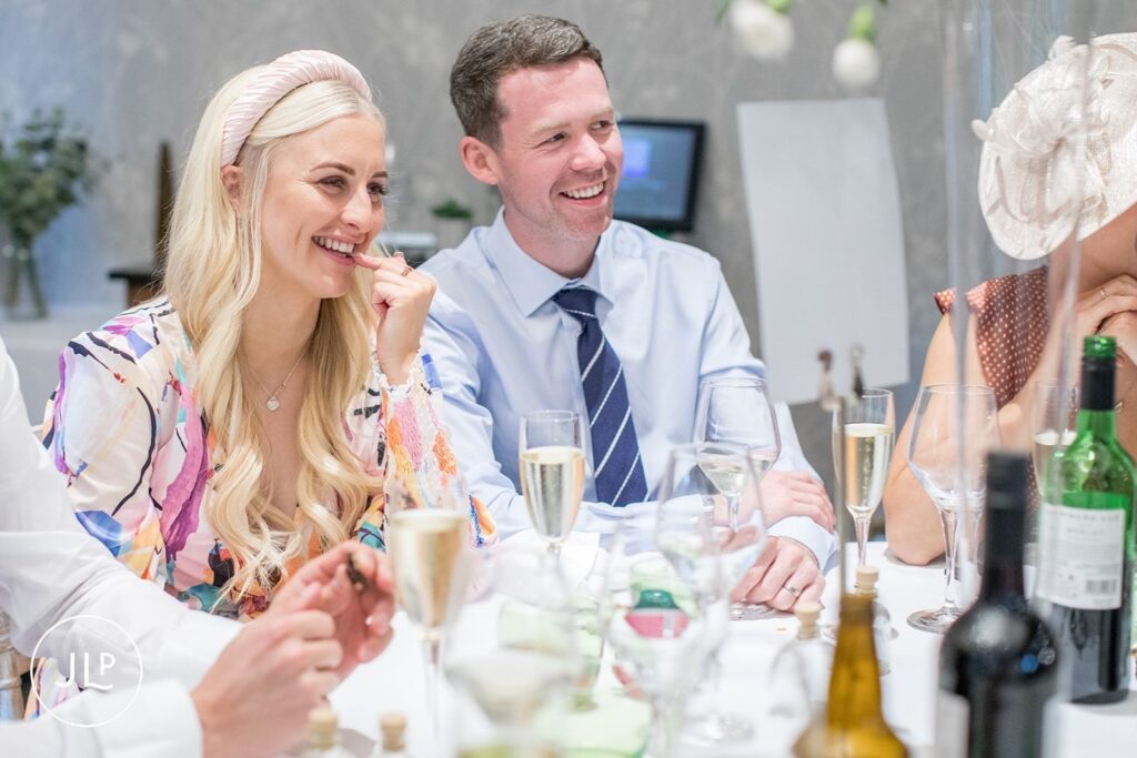 Wedding guests laughing and enjoying drinks at a beautifully decorated table during a Surrey wedding.