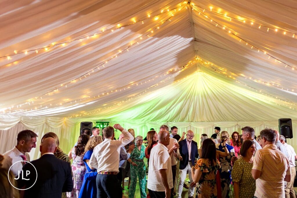 Wedding guests dancing under fairy lights at a beautiful summer outdoor Surrey wedding celebration.