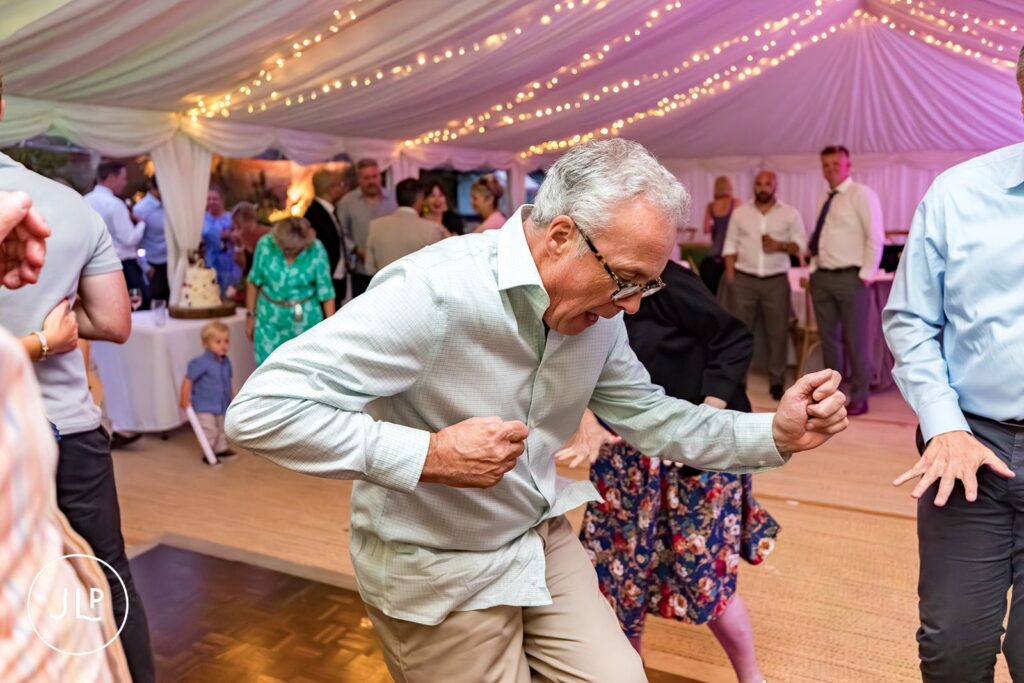Fun candid wedding photography of a guest dancing at a relaxed summer Painshill Park Cobham wedding.