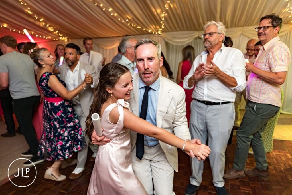 Candid wedding photography of a groom dancing with his daughter in a marquee at Painshill Park.