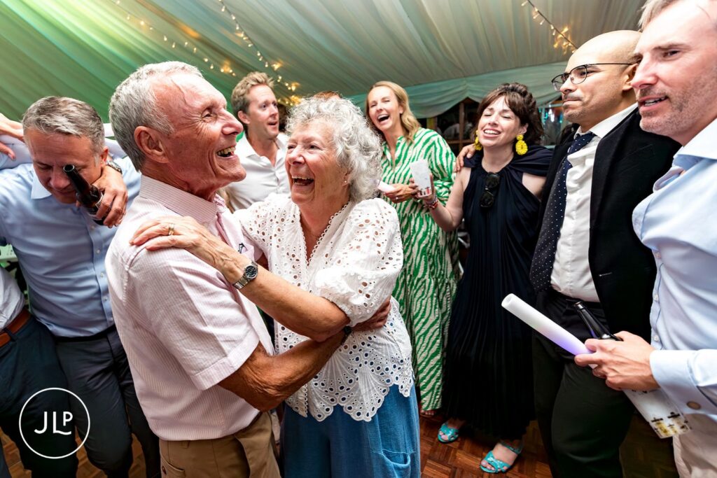 Candid wedding photography of a groom lifting his smiling bride during their marquee reception in Surrey.