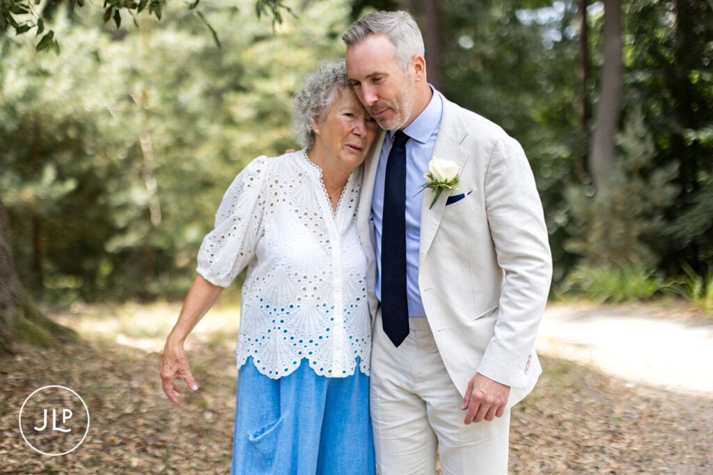 Emotional candid wedding photography of a groom embracing his mother at Painshill Park.