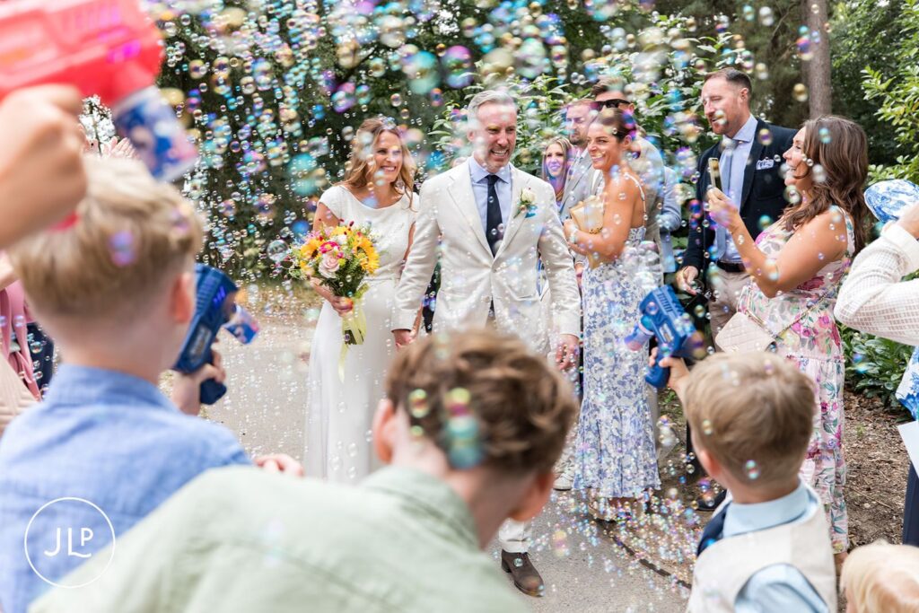 Guests throwing bubble confetti over the newlyweds at a Painshill Park Cobham wedding.