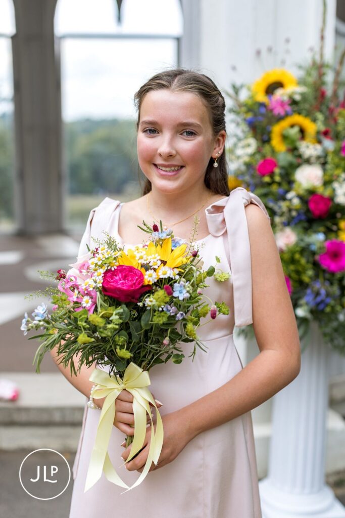 Close-up of the flower girl holding a vibrant sunflower bouquet, captured by a Surrey wedding photographer.