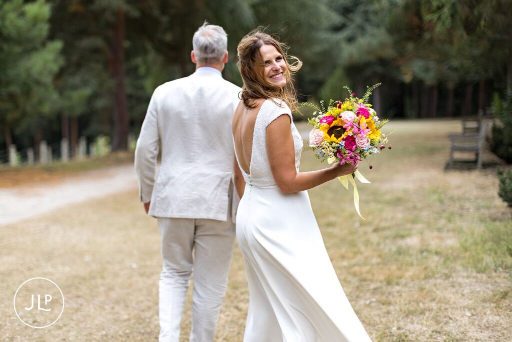 Candid wedding photography of a bride holding a sunflower bouquet at an outdoor Surrey wedding.