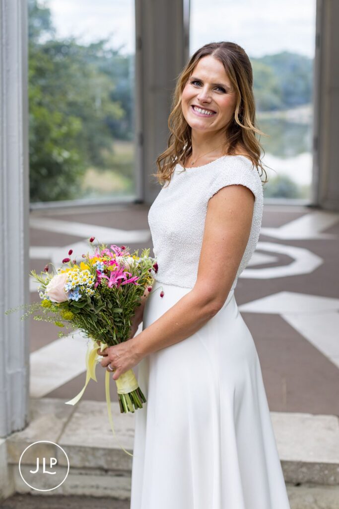 Radiant bride holding a summer wildflower bouquet at her Painshill Park Cobham wedding.