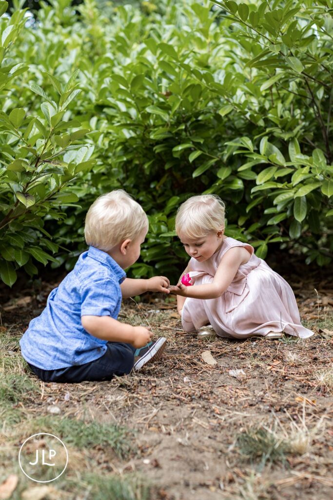 Toddlers sharing a playful moment during a relaxed summer outdoor Surrey wedding ceremony.