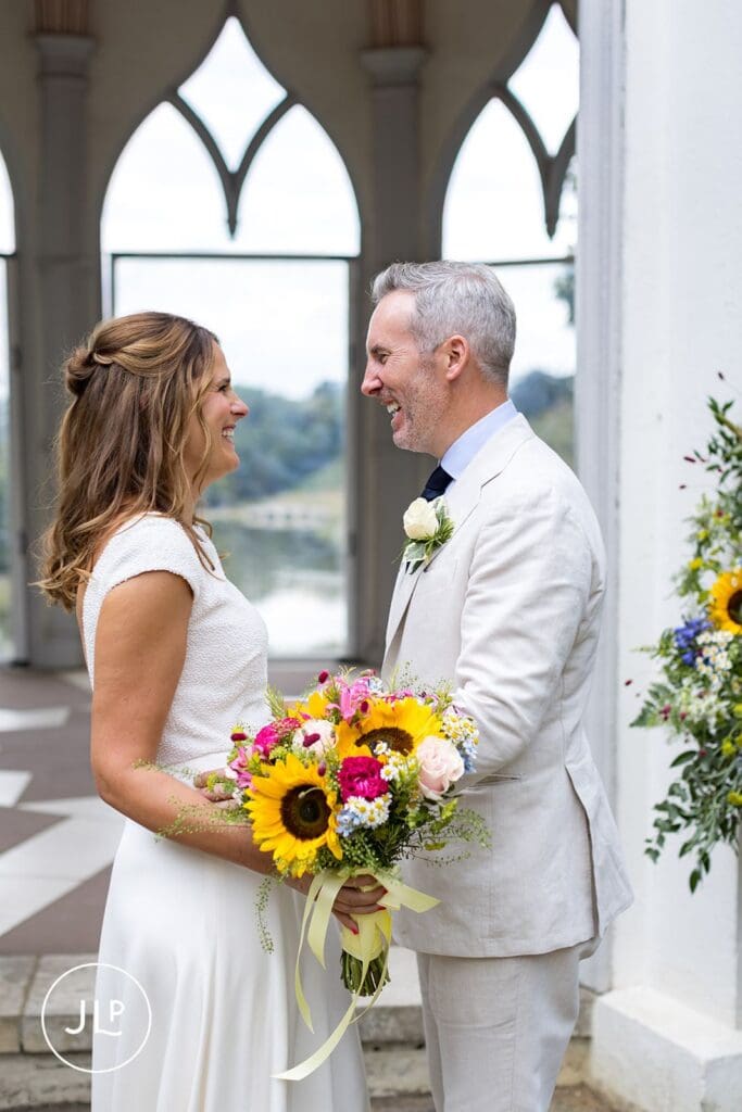Joyful candid wedding photography of a bride laughing with her groom at Painshill Park.