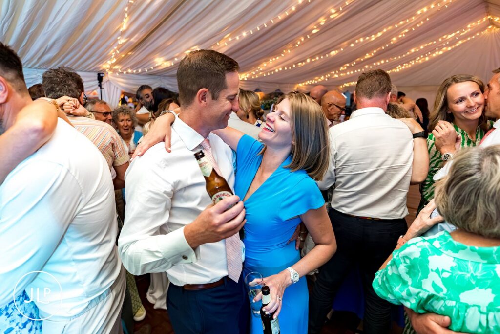 Guests sharing a romantic moment on the dancefloor at an outdoor Surrey wedding reception at Painshill Park.