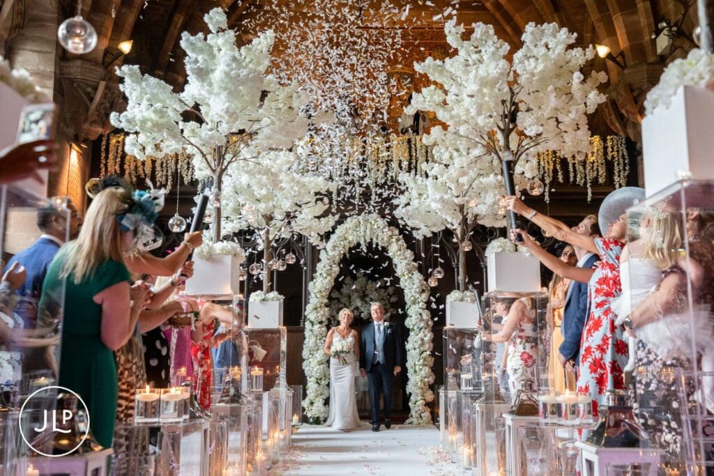Confetti exit celebration at an elegant castle wedding ceremony inside Peckforton Castle Cheshire.