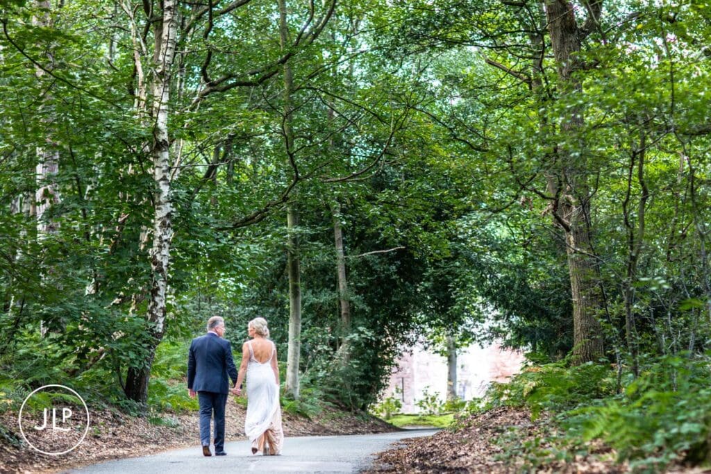 Natural wedding photography of a bride and groom walking through the woods at Peckforton Castle.