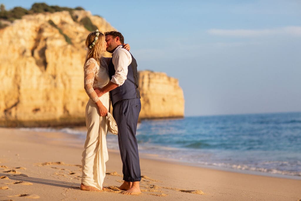 Romantic sunset kiss on the shore, the perfect end to an Algarve beach wedding photoshoot.