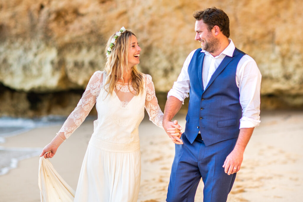 Ali and Matty laughing on the sand during their Algarve beach wedding photoshoot in Portugal.