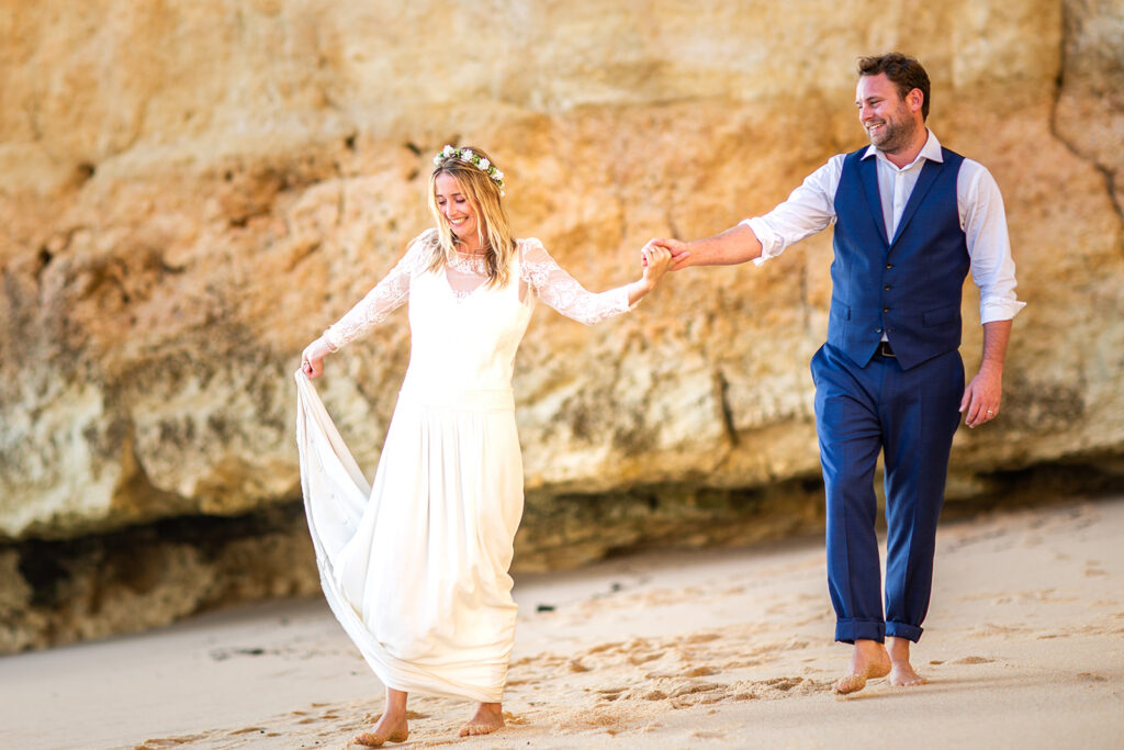Newly married couple walking hand-in-hand, a specialty of this Algarve beach wedding photographer.
