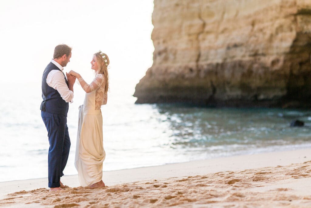 Intimate newlywed moment by a sea cave, captured by a Portugal wedding photographer on the Algarve coast.