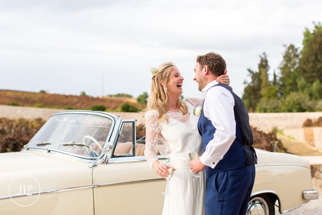 Ali and Matty laughing by their vintage Mercedes at Quinta dos Vales, shot by an Algarve wedding photographer.