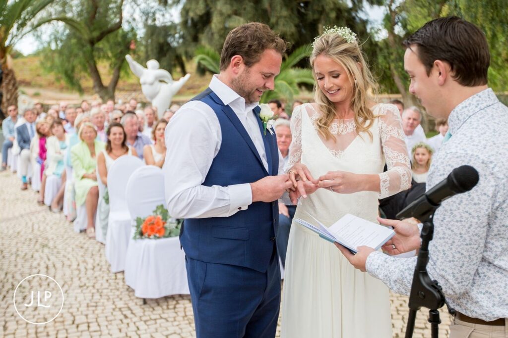 Ali and Matty exchanging rings during a vineyard ceremony, a highlight for an Algarve wedding photographer.