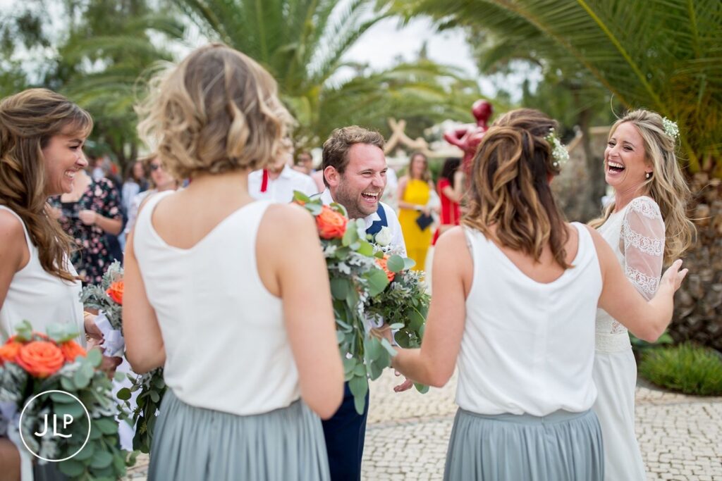 Ali and Matty laughing with bridesmaids after their ceremony, shot by an Algarve wedding photographer.