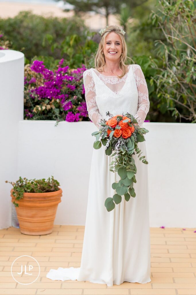 Ali posing in her Mews Bridal gown with an orange rose bouquet, shot by an Algarve wedding photographer.