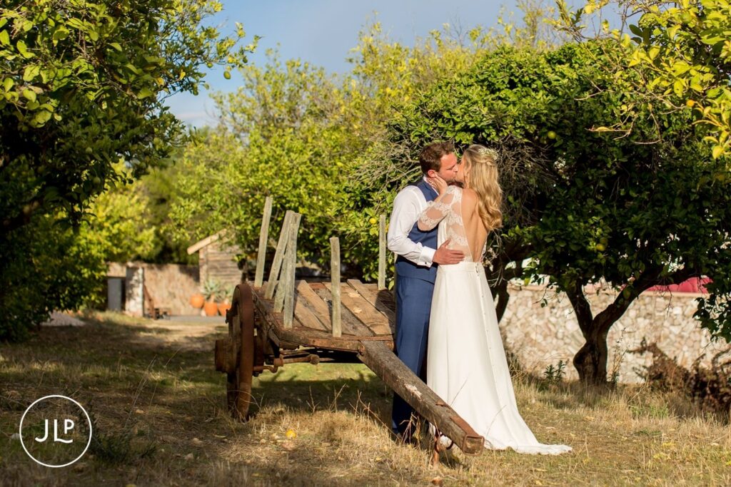Romantic kiss among lemon trees and vineyards, captured by a Quinta dos Vales wedding photographer.