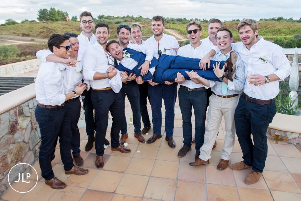 Groomsmen lifting Matty during a fun celebration moment at a luxury Algarve wedding at Quinta dos Vales.