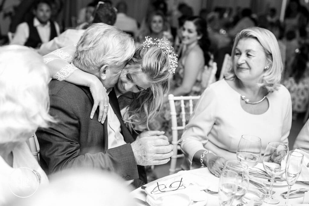 B&W candid of an emotional hug during the wedding speeches, captured by an Algarve luxury wedding photographer.