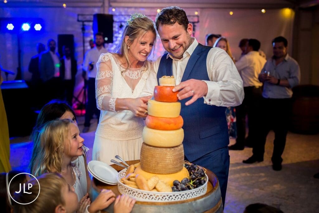 Ali and Matty cutting their iconic cheese tower wedding cake at a luxury Algarve wedding celebration.