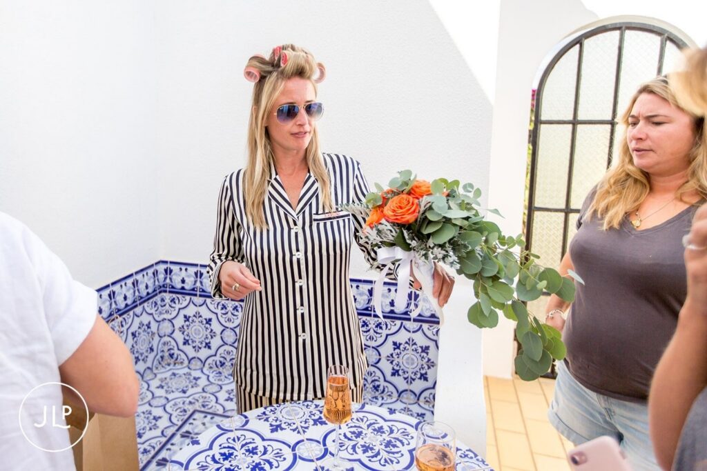 Bride in striped pajamas holding her wedding bouquet during a luxury Algarve wedding morning at a private villa.