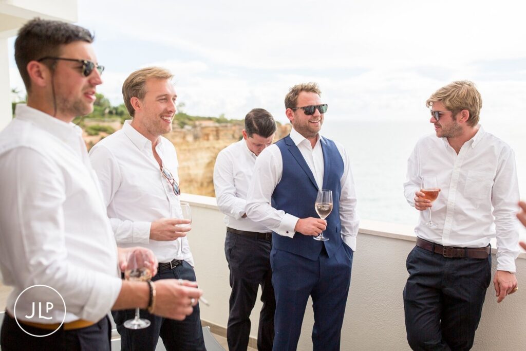 Matty and groomsmen enjoying drinks with an ocean view, captured by an Algarve luxury wedding photographer.