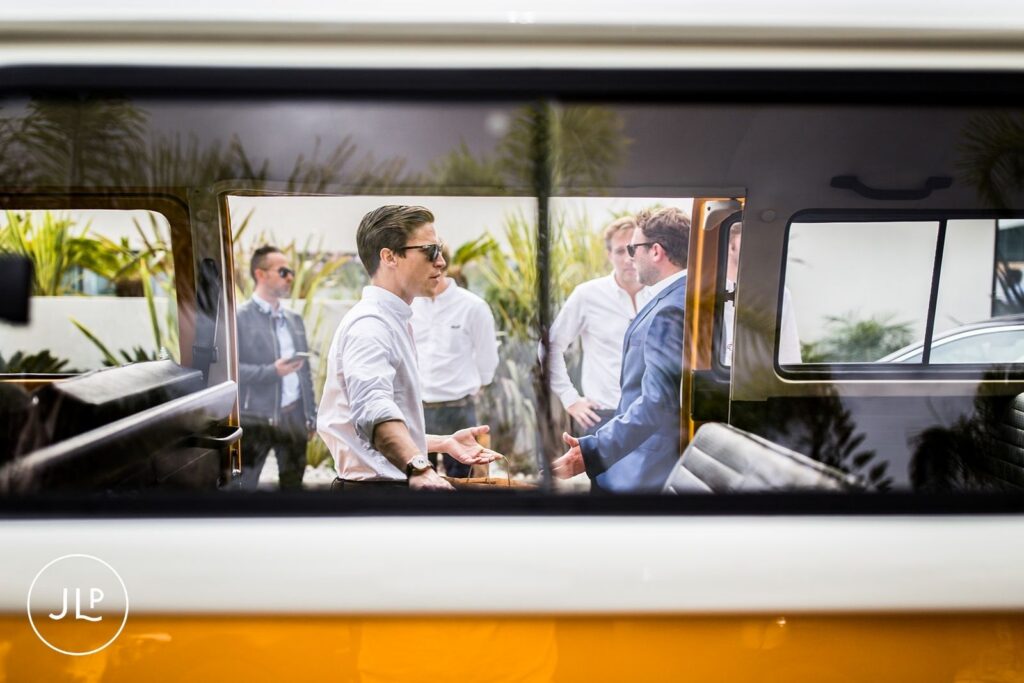 Creative shot of the groom and friends through a vintage camper van window at a Portugal destination wedding.
