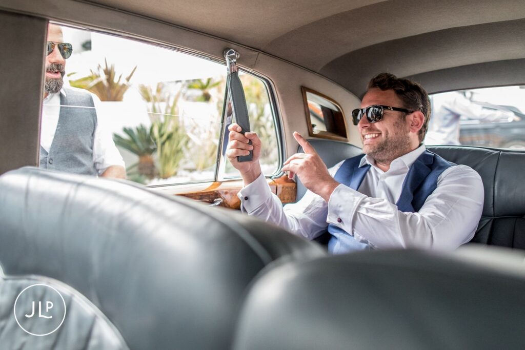 Matty laughing inside a luxury wedding car on his way to a destination wedding ceremony in Portugal.
