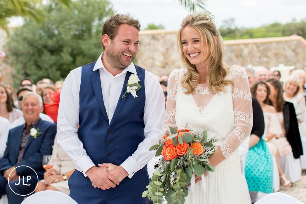Ali and Matty smiling at each other during their outdoor wedding ceremony at Quinta dos Vales, Portugal.