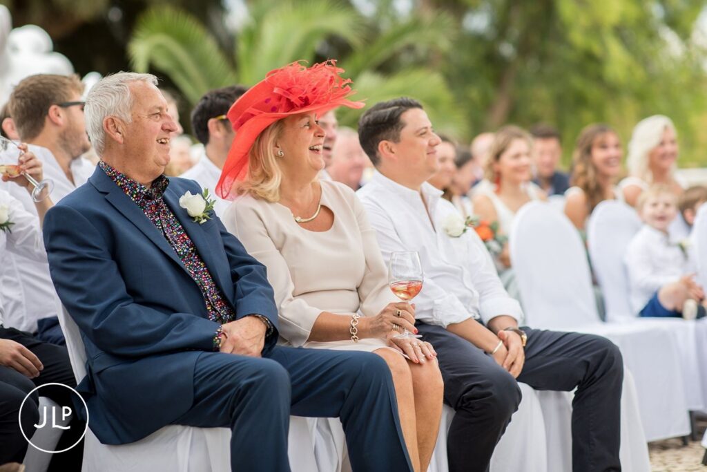 Wedding guests laughing during an outdoor ceremony, shot by an Algarve luxury wedding photographer.