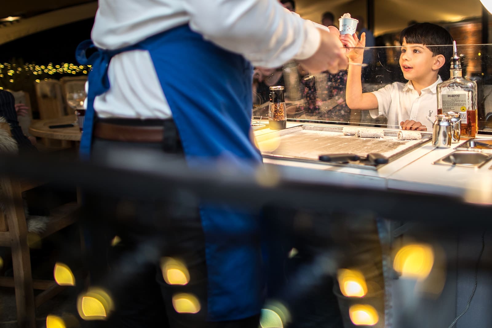 A young boy eagerly receiving rolled ice cream from a caterer at an evening Berkshire wedding reception.