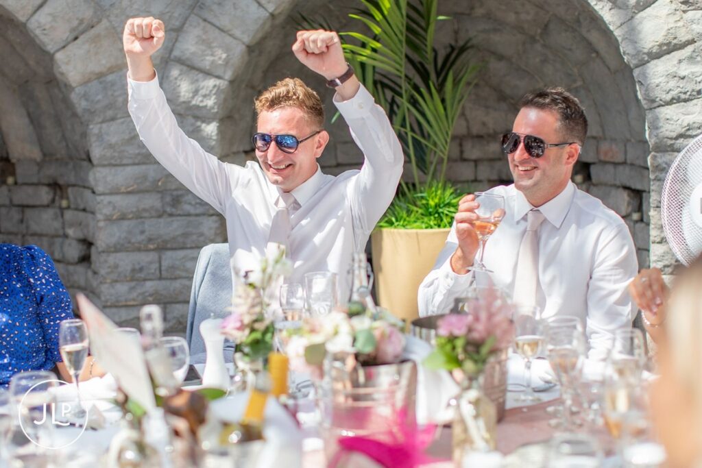 Two groomsmen wearing sunglasses cheer and raise a toast during the reception at De Vere Tortworth Court.