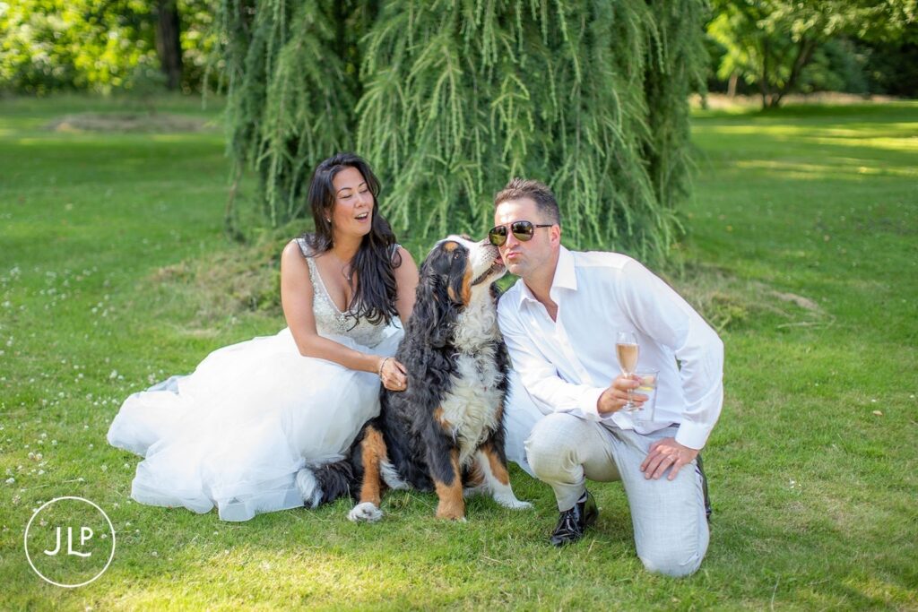 Mel and Ben posing with their Bernese Mountain Dog, a highlight of natural wedding photography Gloucestershire.