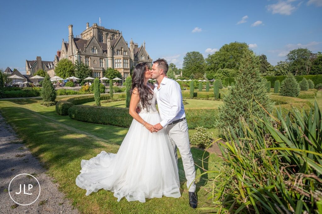 Bride and groom sharing a kiss in the manicured gardens, captured by a Tortworth Court wedding photographer.