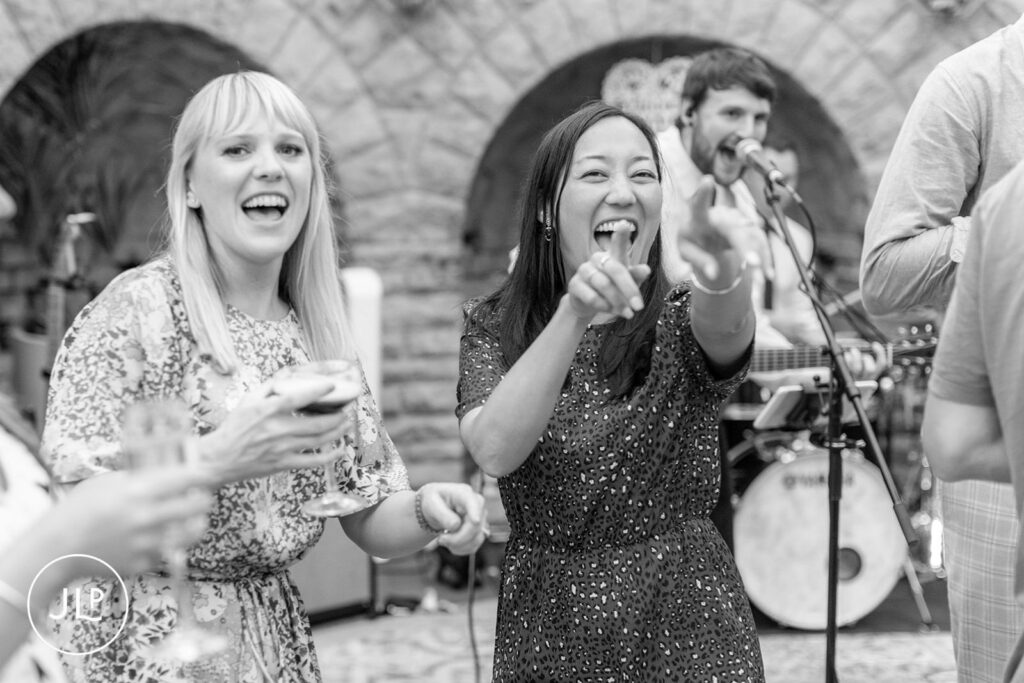Guests pointing and laughing while dancing, featuring the style of a candid wedding photographer UK.