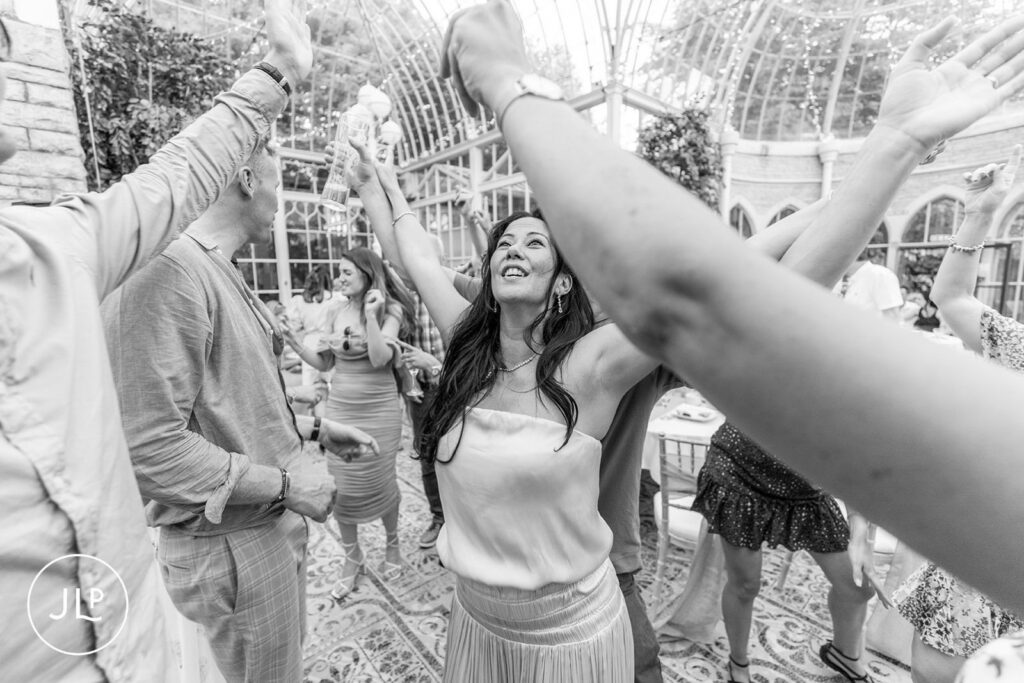 Mel dancing with friends under the glass ceiling of a luxury Gloucestershire wedding venue.