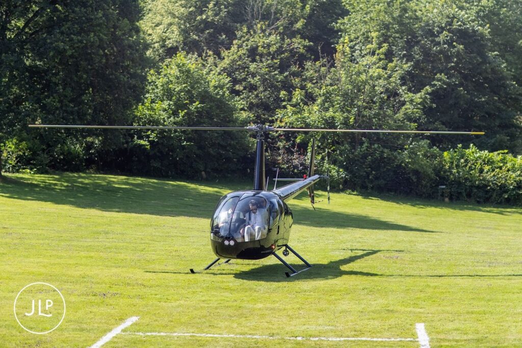 A black helicopter landing on the lawn for a dramatic entrance at a De Vere Tortworth Court wedding.