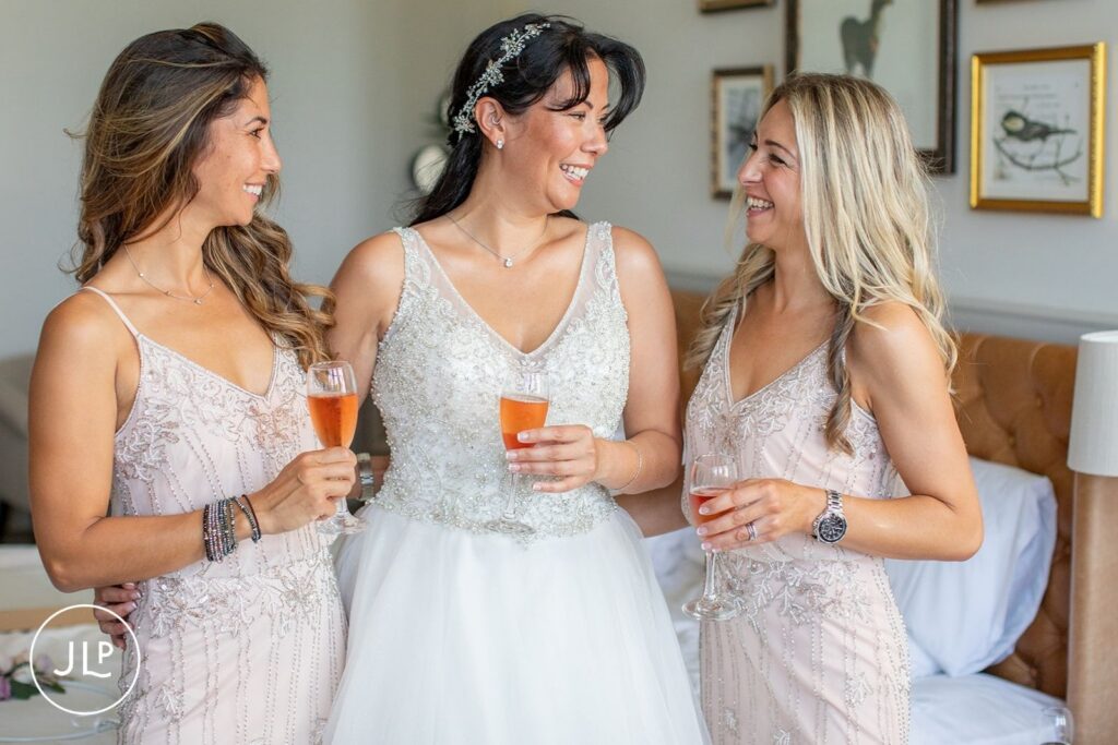 The bride and two bridesmaids in beaded pink gowns share a toast with rose champagne.
