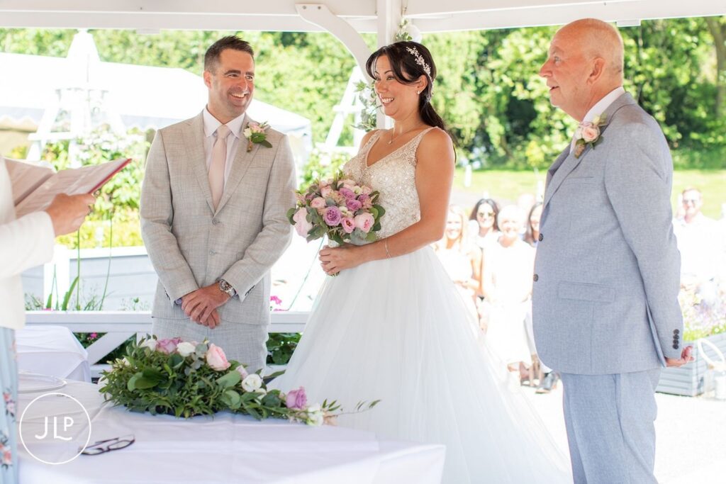 The bride and groom smile at each other during their outdoor ceremony at De Vere Tortworth Court.